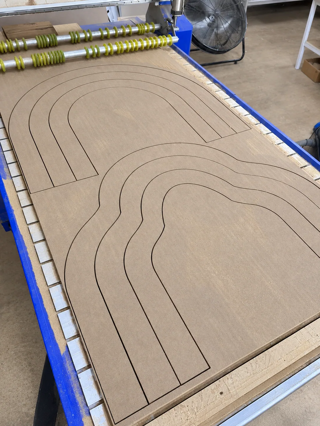 Hoja de MDF con los arcos ya cortados sobre la mesa del router CNC